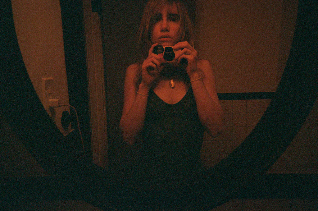 Model takes a mirror photo, wearing a black bodysuit