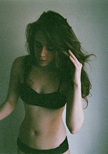 Woman wearing black bralette with matching low-rise panty.