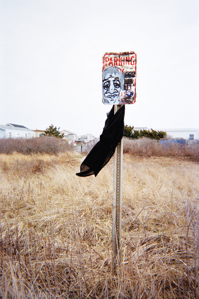 Field with a parking sign stand, holding a black dress
