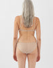 Back view of woman wearing nude panty with nude trim, and matching bralette.