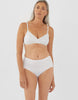 Woman wearing white high-waist cotton panty with white scallop trim on waist and leg openings with matching bralette. 