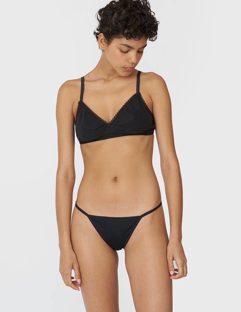 A woman wearing a black cotton bralette and thong.
