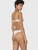 Back view of woman wearing white cotton thong with white trim and matching bra.