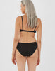 Back view of woman wearing araks organic cotton black isabella panty with white trim, and matching bralette.