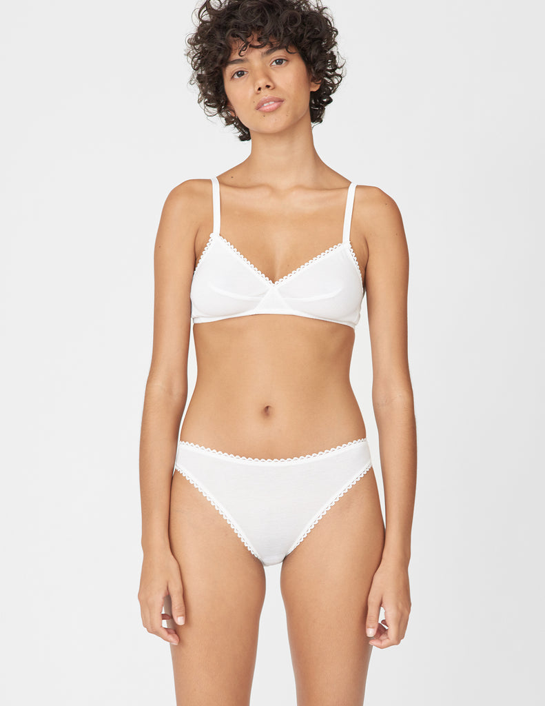 Front view of woman wearing white bralette with white trim and matching panty.
