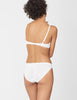 Back view of woman wearing white bralette with white trim and matching panty.