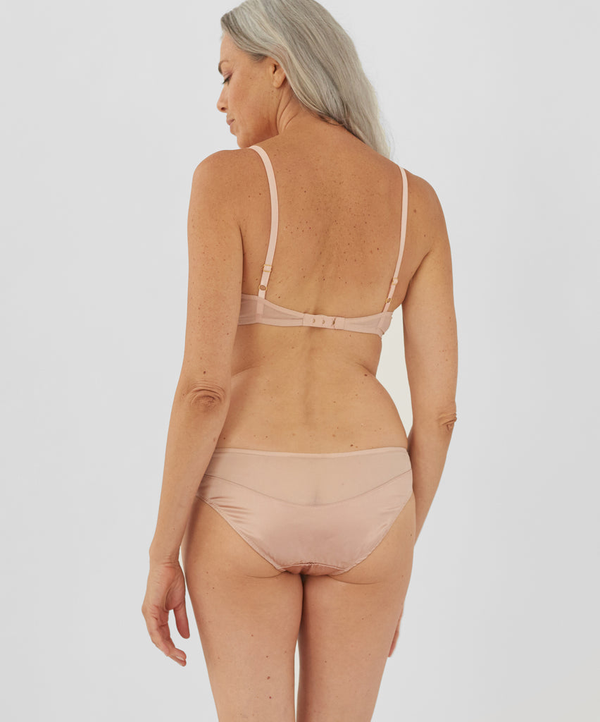 Back view of woman wearing beige bralette and matching panty.