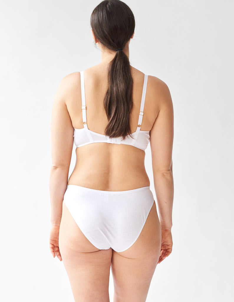 back view of a woman wearing a white bra and matching panty.