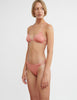 woman wearing pink triangle bikini top with knotted back and matching bottom by Araks