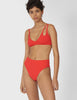 Front view of woman wearing a red bikini top with asymmetric crisscross straps with matching bottoms