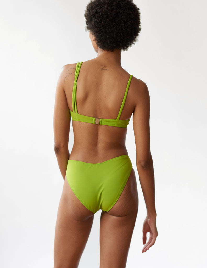 back of woman wearing green bikini top with asymmetric straps and matching bottoms