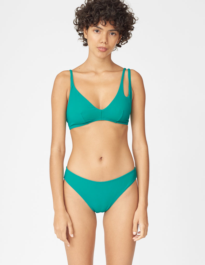 Front view of woman wearing an green bikini top with asymmetric crisscross straps with matching bottoms