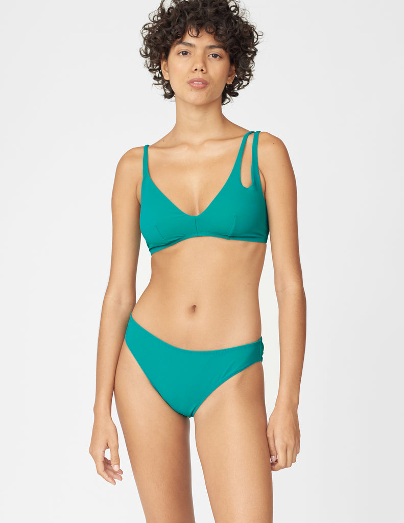 Front view of woman wearing an green bikini top with asymmetric crisscross straps with matching bottoms
