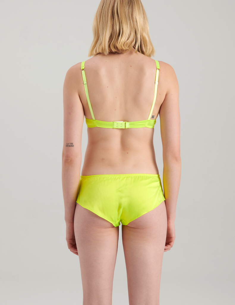 A woman wearing a yellow silk underwire bra and short by Araks
