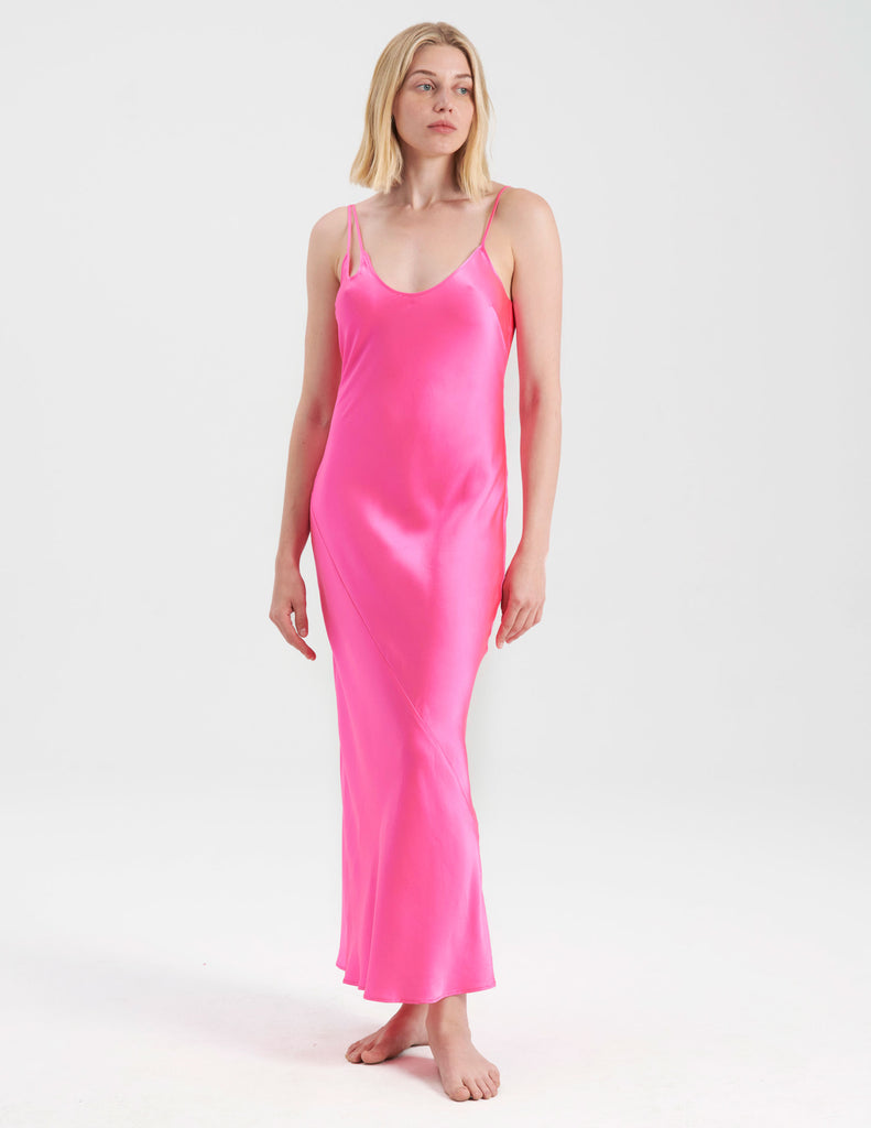 A woman wearing a long bright pink silk slip
