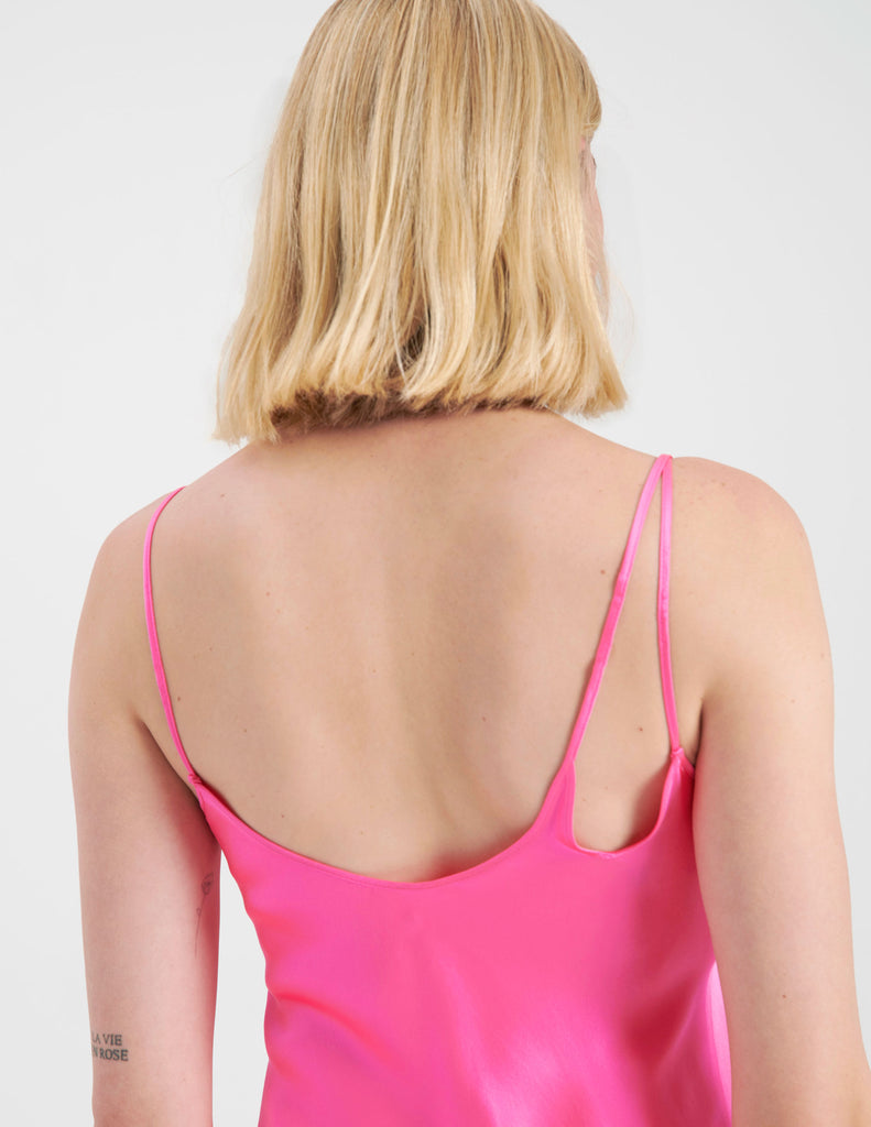 A back detail shot of A woman wearing a long bright pink silk slip