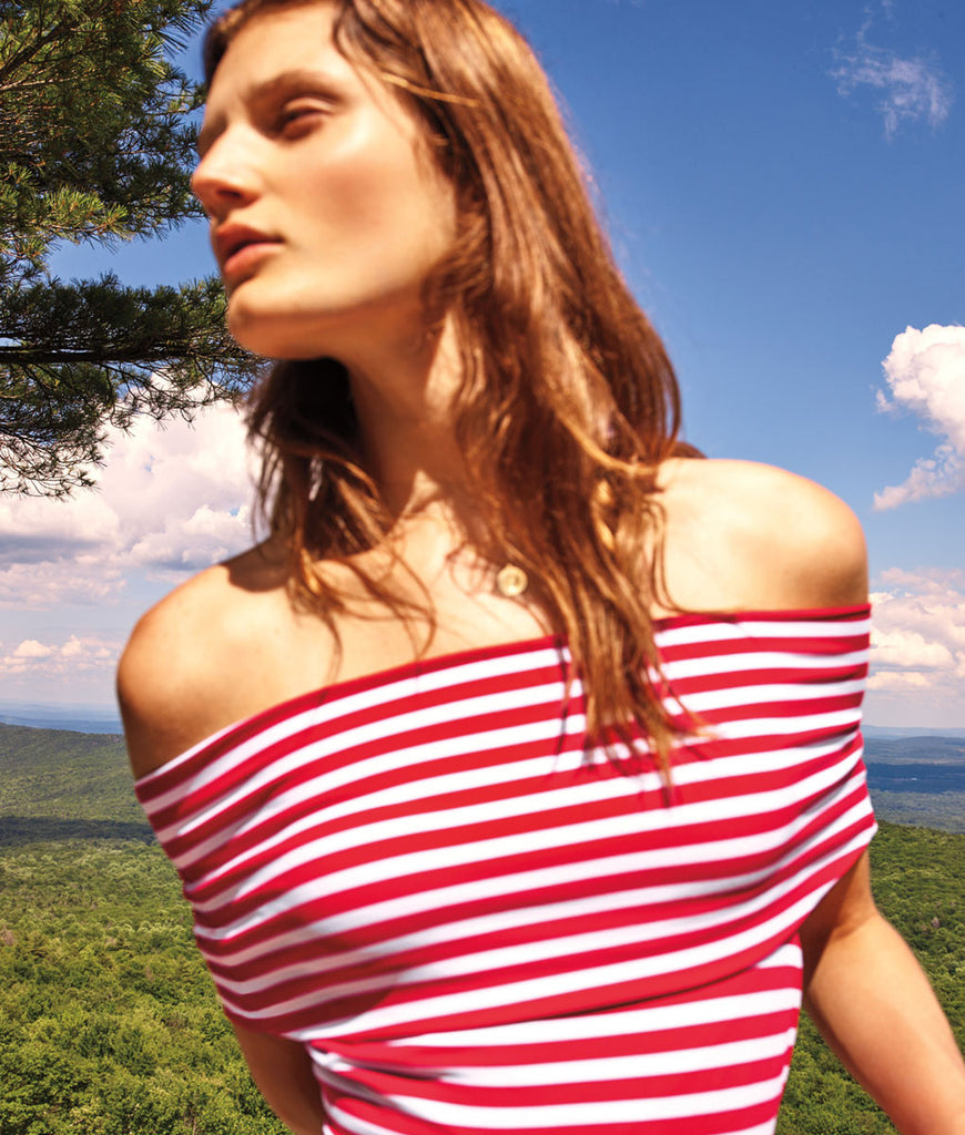 Woman in field wearing red and white stripe off the shoulder one-piece. 