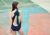 Back shot of woman wearing blue and green one-piece.  Edit alt text