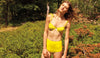 Woman in a field wearing a yellow underwire bikini top with shoulder ties with matching high-waisted swim bottoms.
