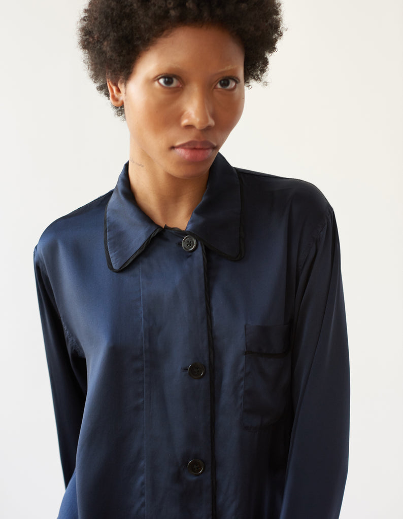 A woman wearing a navy blue silk long sleeve pajama top with collar.