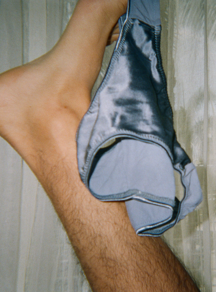 A blue silk panty dangling from a foot