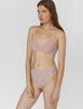 Front view of woman wearing beige, lace underwire bra and matching mid-rise panty.