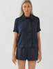 Woman wearing navy silk collared short-sleeved sleep shirt with left breast pocket and contrast piping and matching shorts