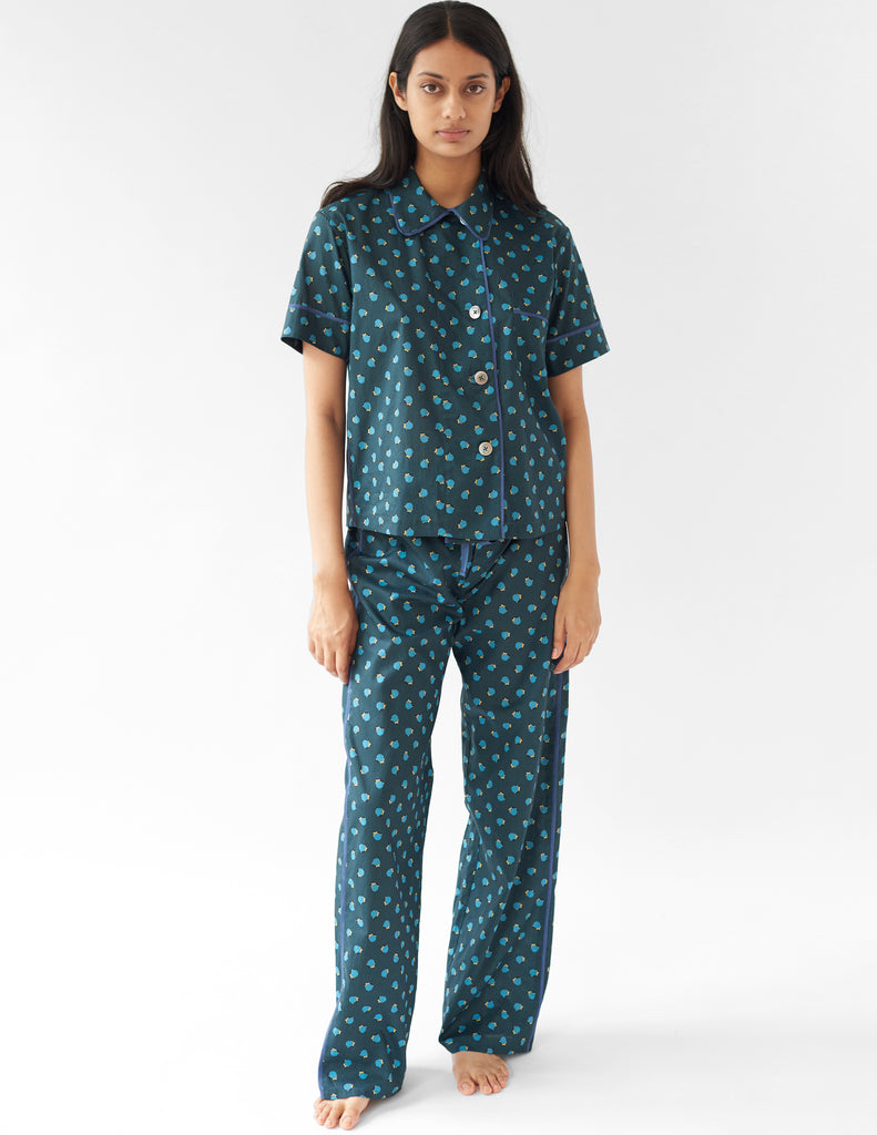 woman wearing green cotton pajama top with blue trim and polka dot print and matching pants by Araks