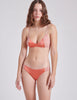 FRONT VIEW OF WOMAN WEARING ORANGE SILK BRA AND PANTY