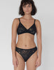 Woman wearing Black, lace mid-rise panty with matching wireless bralette.