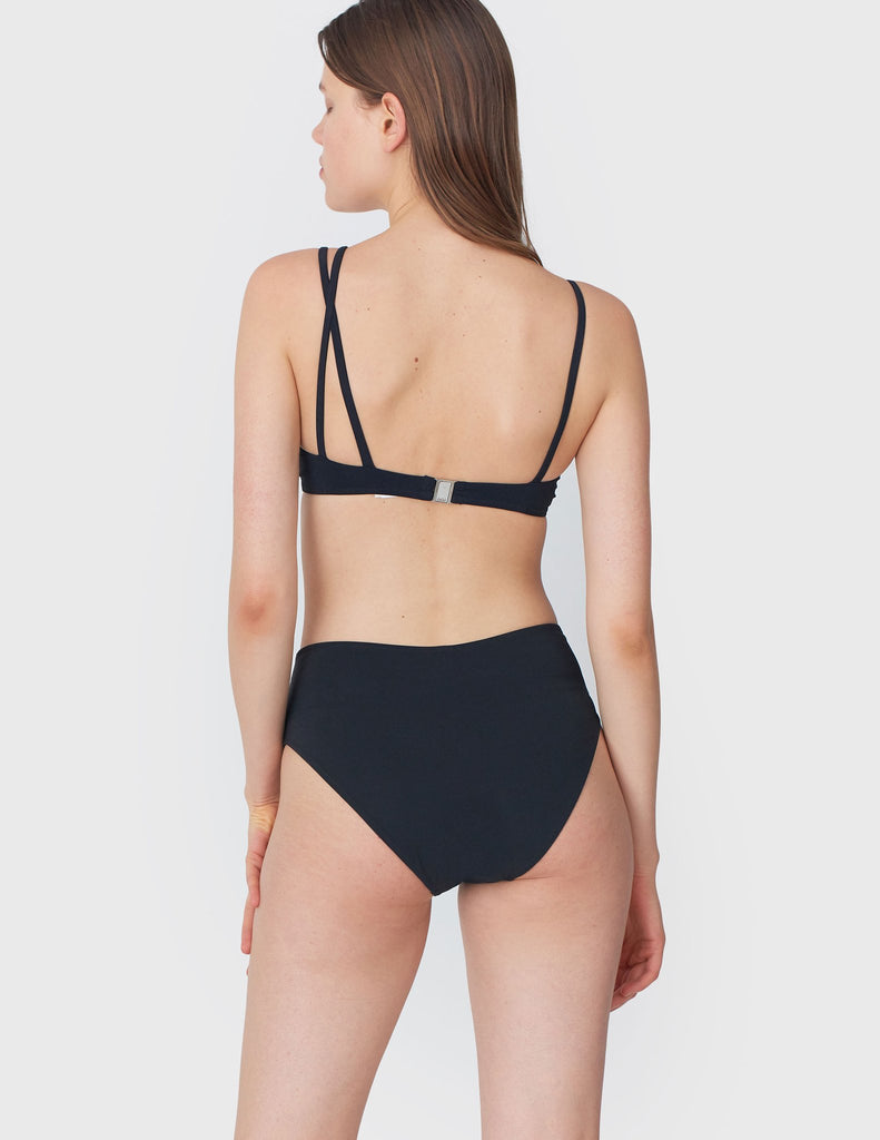 Back view of woman wearing an black bikini top with asymmetric crisscross straps with matching bottoms