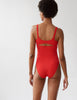 back of woman in red one piece with cutout