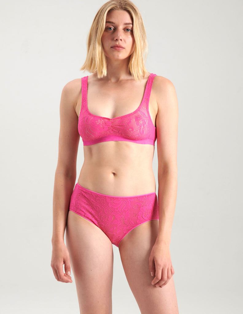 A woman wearing a bright pink lace bralette and panty.