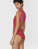 Woman wearing pink and red one piece swimsuit with a split neckline and doubled one shoulder strap