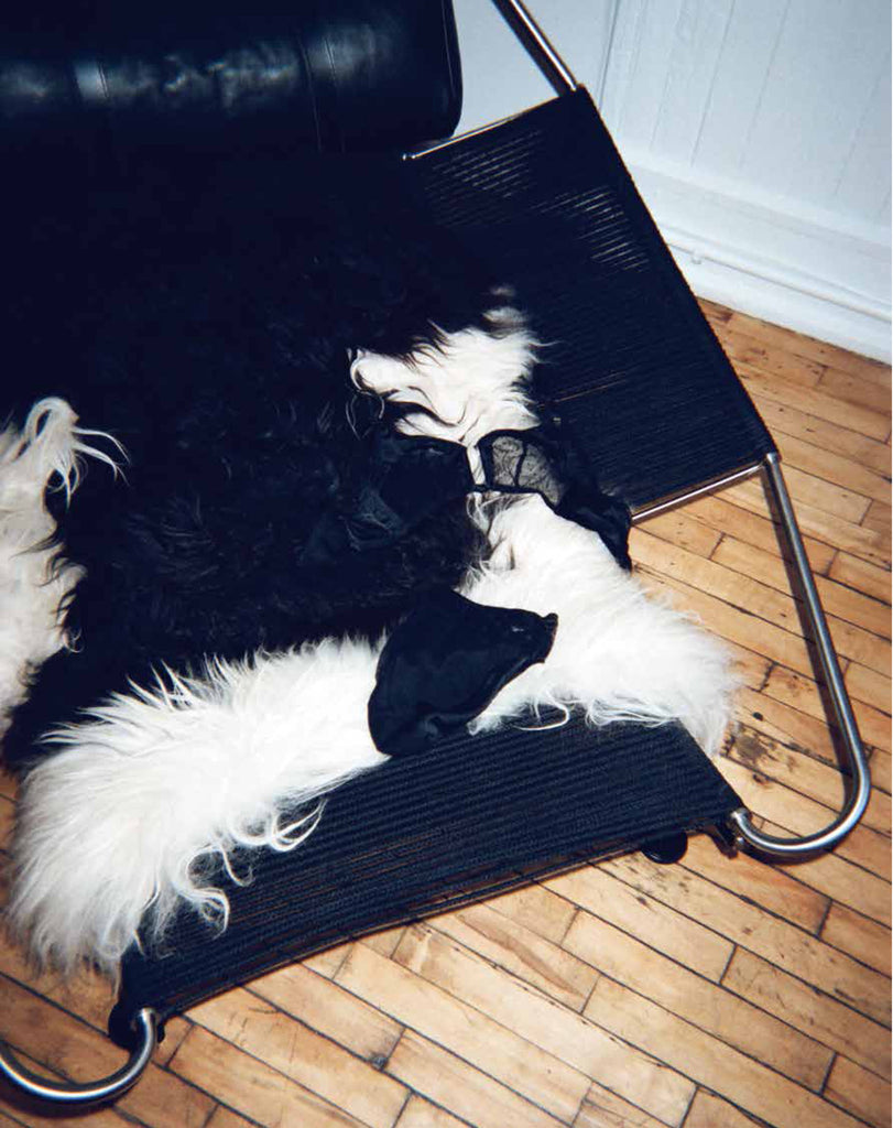 A chair with a fur pillow, displays black bralette and matching panty