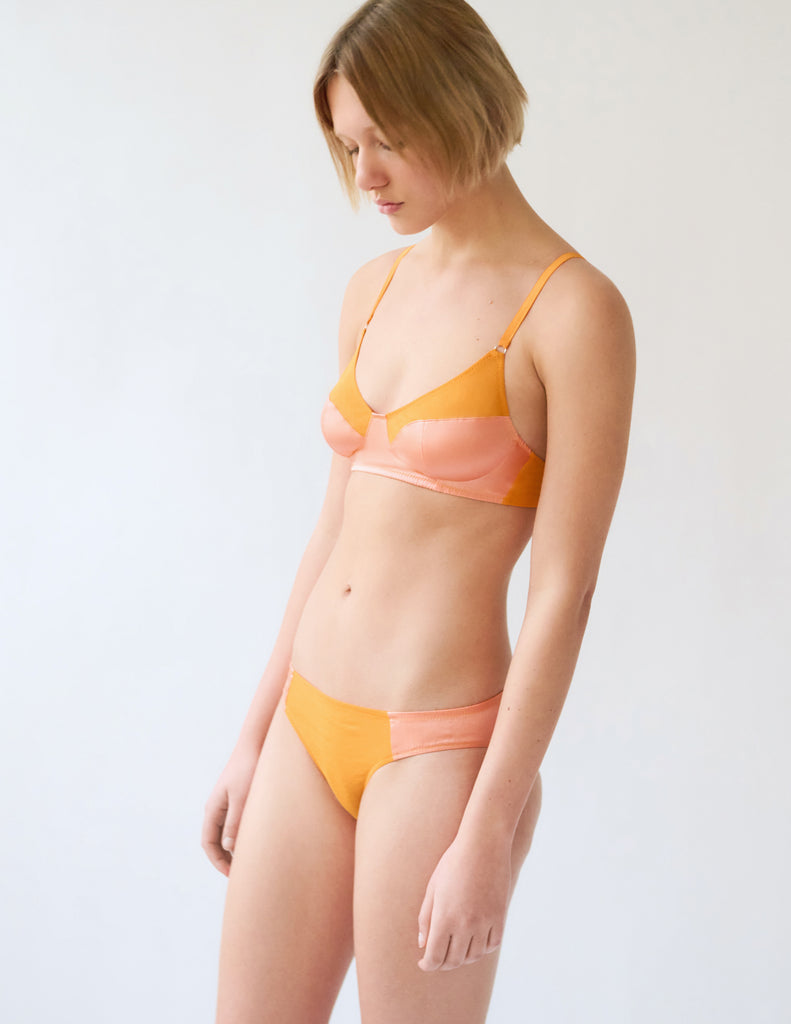three quarter of woman in orange silk bra and panty