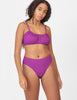 Front view of woman wearing a purple bikini bottom with matching purple bikini top