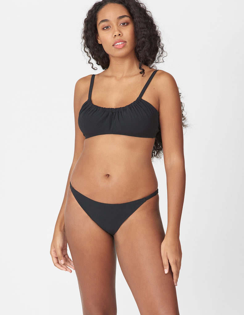 Front view of woman wearing a black bikini bottom with matching black bikini top