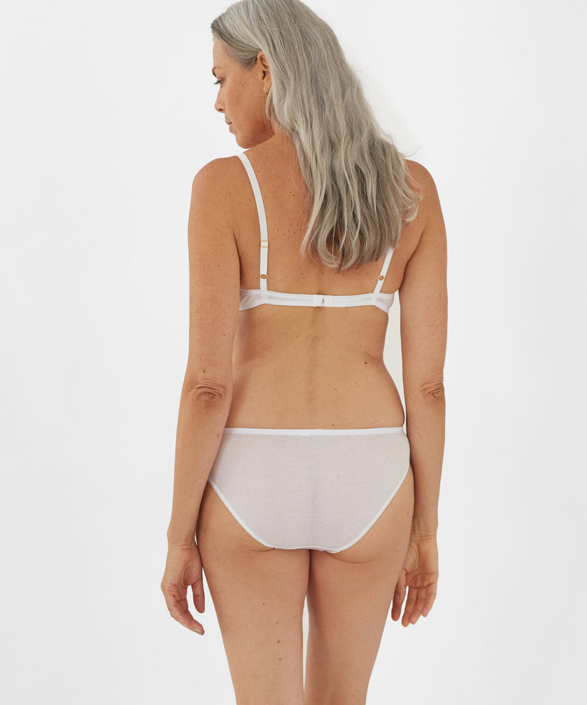 Back view of model wearing white bralette and matching panty. 