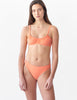 Woman wearing peach mid-rise swim bottoms with matching bikini top