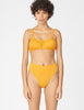 Front view of woman wearing a yellow bikini bottom with matching yellow bikini top