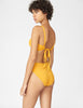 Back view of woman wearing a yellow bikini top with matching bikini bottom