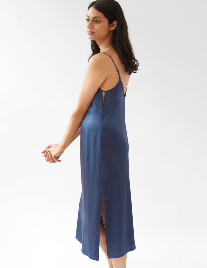 side view of woman wearing v neck blue silk slip with slit by Araks